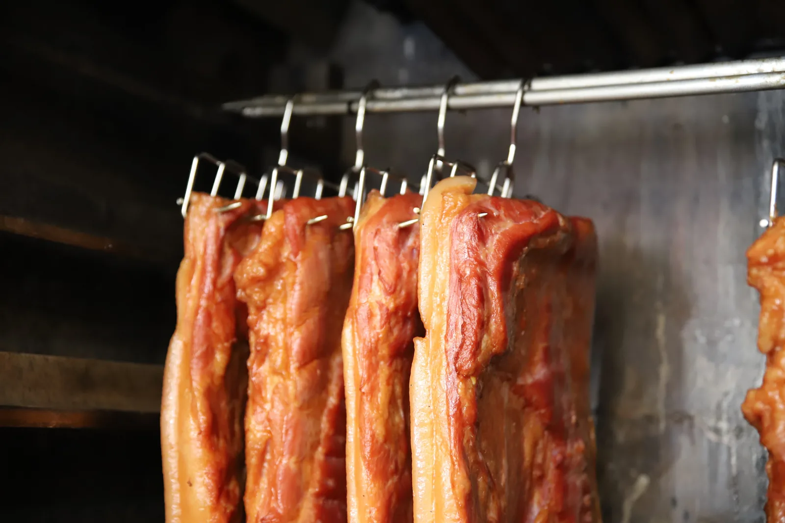 Slabs of bacon hanging in the smokehouse